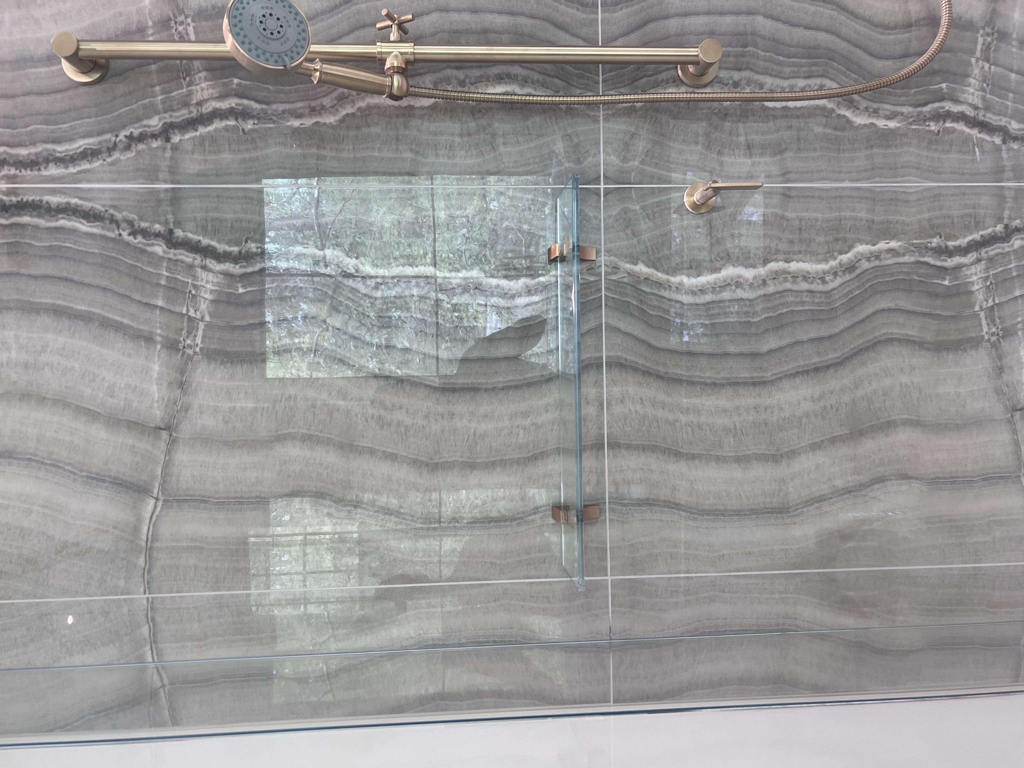 This tiny floating shower shelf features brushed bronze clamps which match well with the existing shower hardware!