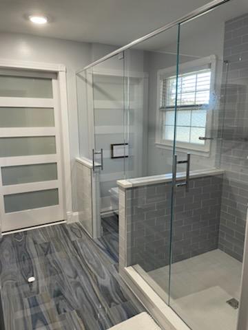 This shower door and toilet partition combination is becoming more popular! This style features two swinging doors with a header system and a half panel on the half wall.