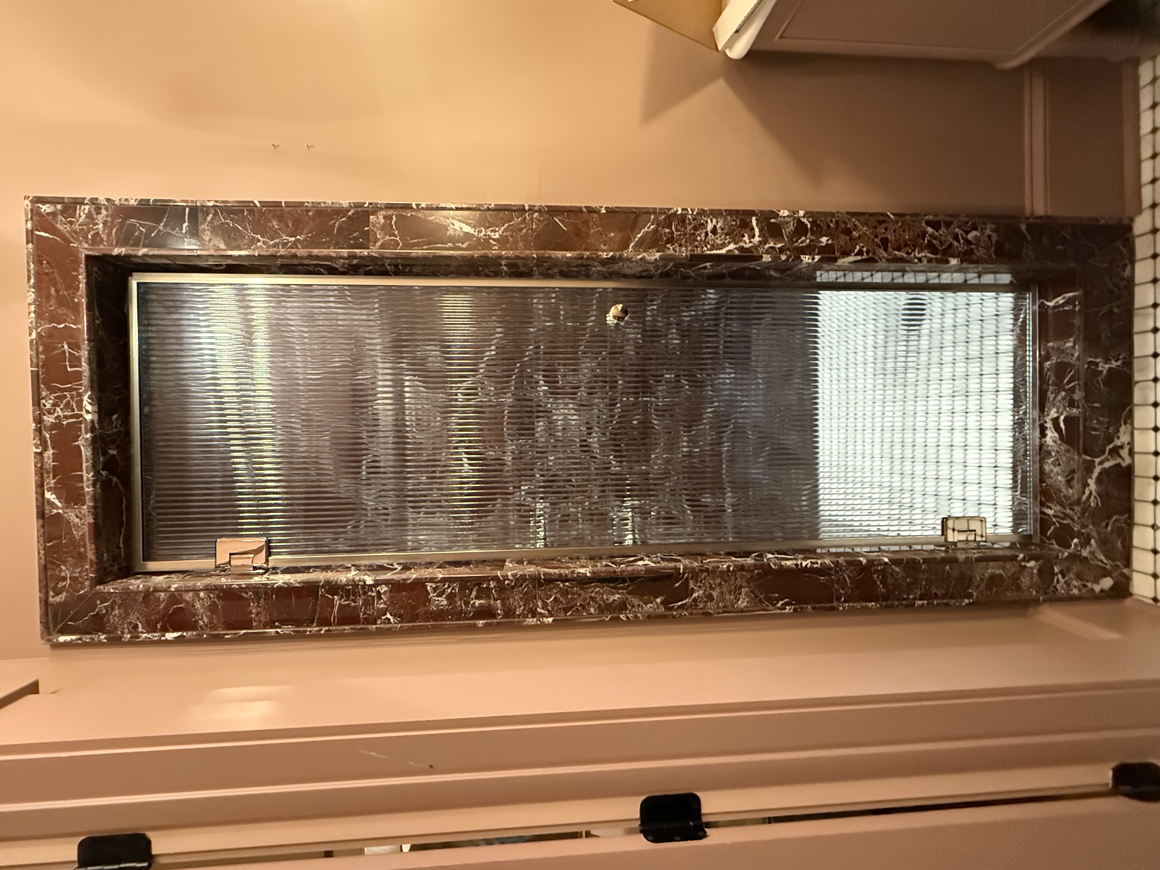 This is a vertical reeded glass shower door with a warm polished nickel wrap and knob. Amazing design from Emily Lambert Designs!