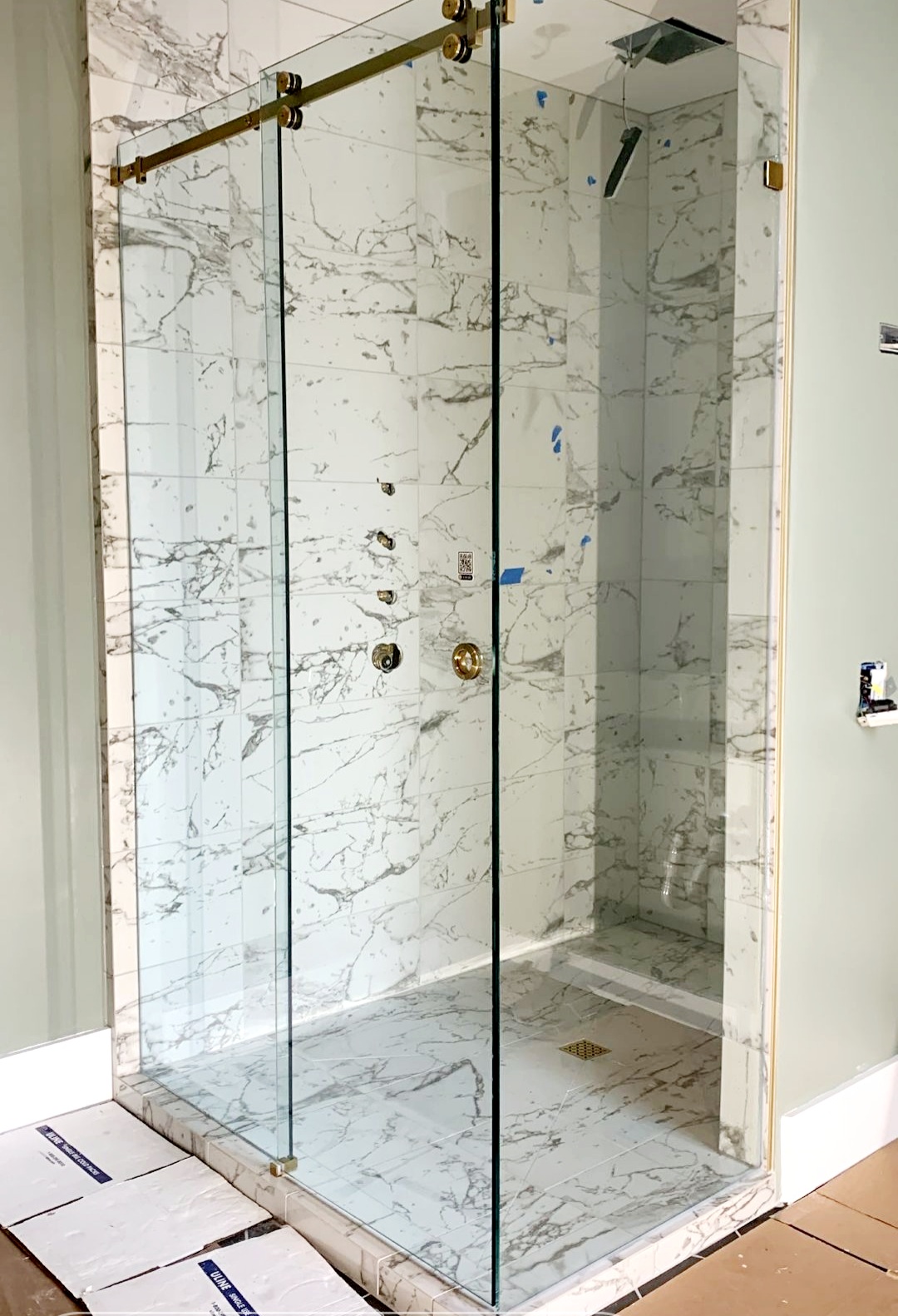 A gorgeous Serenity style sliding shower door in brushed gold from Structure Glass Solutions! The finger cup on the door allows the door to bypass the fixed panel to maximize the opening width.