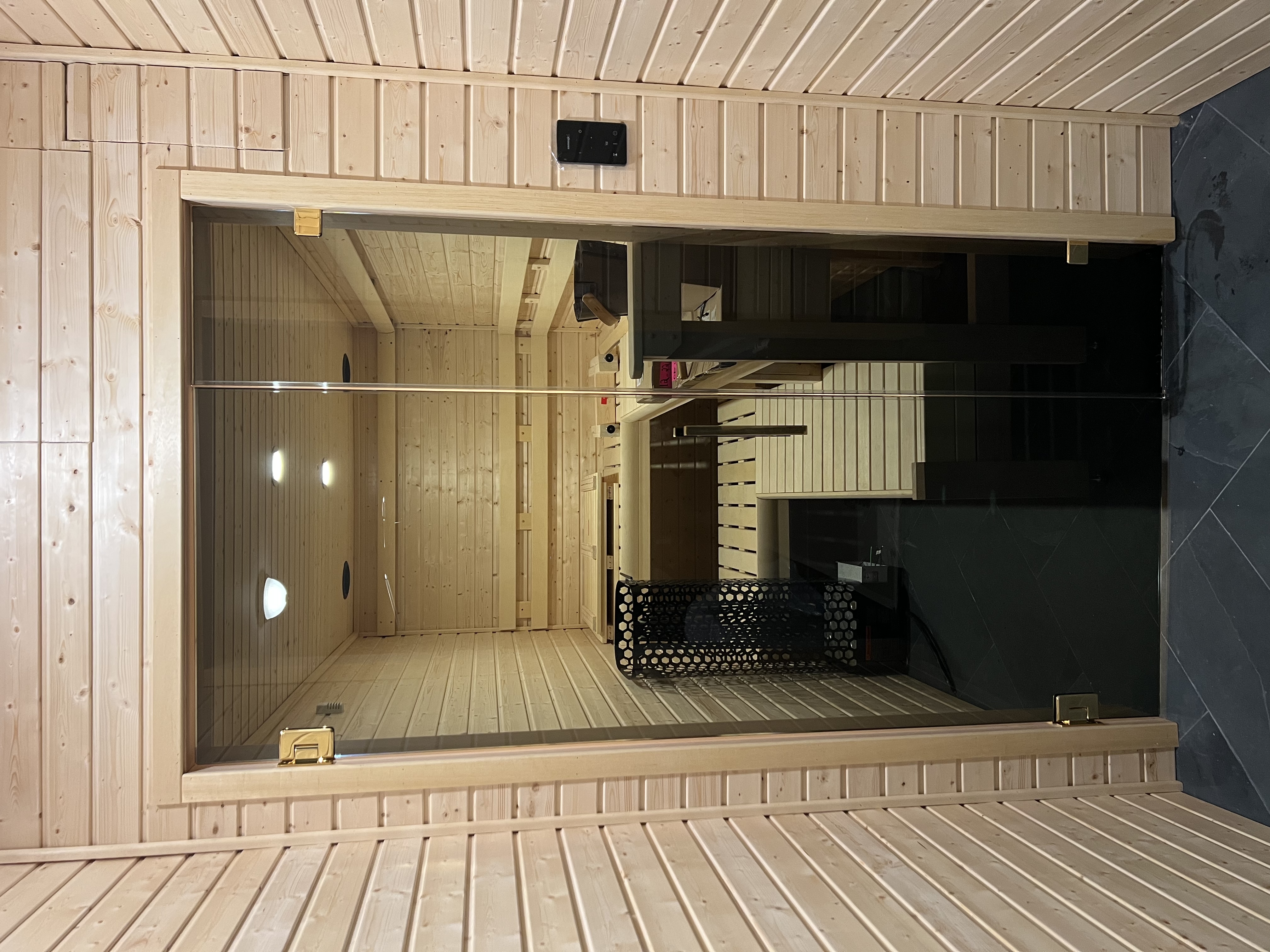 Tinted glass sauna enclosure with polished brass hardware and a wooden handle!